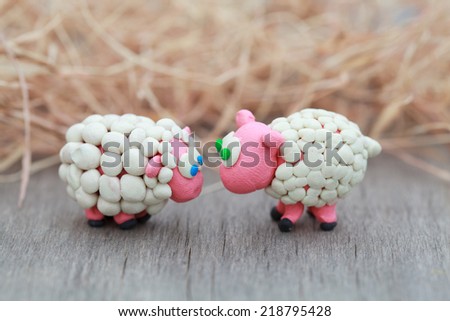 Plasticine world - little homemade white sheep with blue and green eyes stand on a farm on background of hay, selective focus and place for text