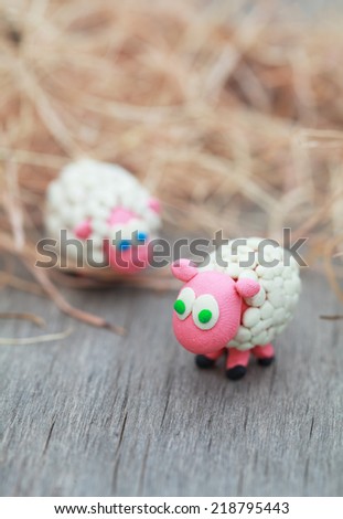 Plasticine world - little homemade white sheep stand on a farm on background of hay, selective focus on the first