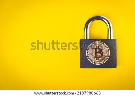Cryptocurrency is banned. bitcoin transfer ban. Rate drop. Bitcoin coin and padlock on yellow background.