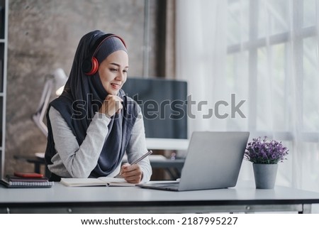Muslim female fighter studying online and greeting video call smiling arab woman taking notes and work on laptop
