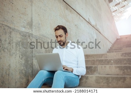 young man working with computer on stairs and sun shining