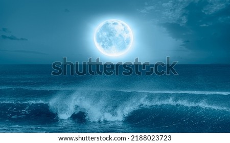 Night sky with blue moon in the clouds sea wave in the foreground "Elements of this image furnished by NASA