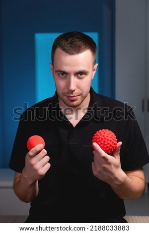 Portrait of a smiling young man holding stress balls, massage therapist