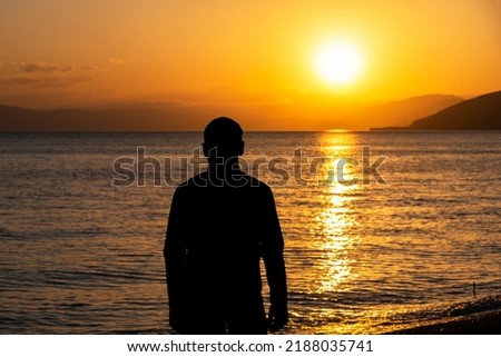 man at sunset, silhouette in the sea