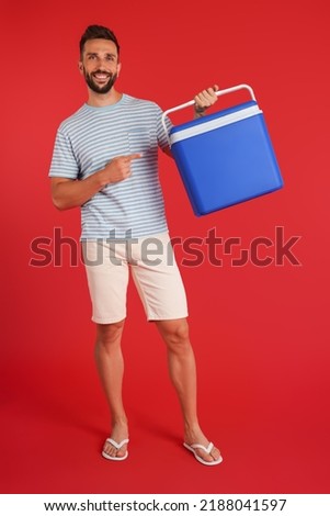 Happy man with cool box on red background