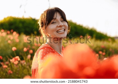 beautiful girl in a field with poppies in a red dress