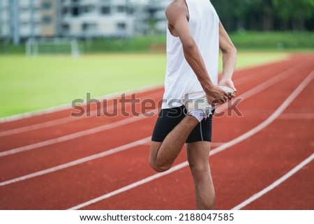 Athletes sport man runner wearing white sportswear to stretching and warm up before practicing on a running track at a stadium. Runner sport concept. Royalty-Free Stock Photo #2188047585