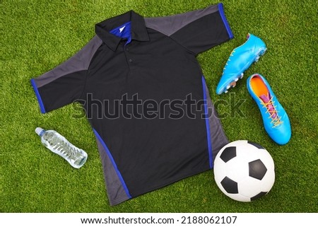 Flatlay of sportswear or trendy soccer clothes, accessories and equipment on grass background. above view of modern sporty, active or fitness wear clothing style with water bottle, ball and trainers