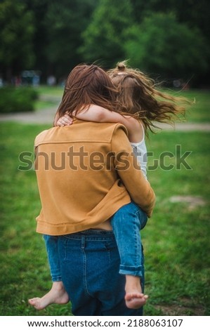 mother holds her daughter in her arms. the daughter numbs the mother by the neck. portrait