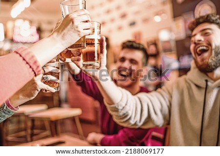 Happy friends at pub cafe raising beer glasses for a celebratory toast - filtered image - beverage and people lifestyle concept