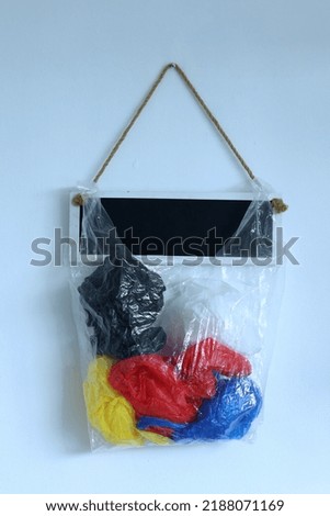 A bag of plastics and globe earth hanging on the white wall background with empty blank board for text. The concept of World Environment Day.
