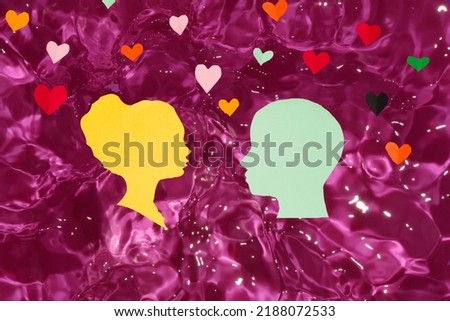 male and female paper head looking at each other in pink water, hearts around them, creative art design, love in the water