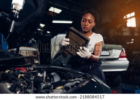 Woman auto mechanic checking air filter and repair maintenance auto engine is problems at car repair shop.