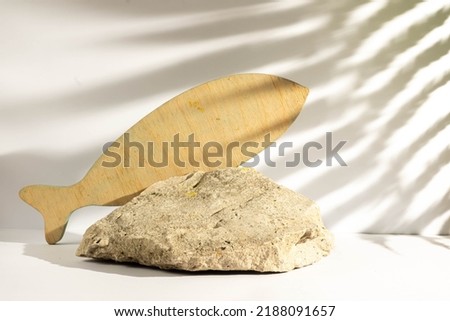  Podium embossed stone and wooden fish silhouette for products presentation. Monochrome template for mockup. Sea style