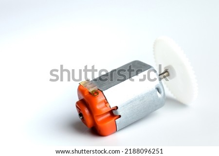 Direct current electric motor with white gear attached to it shaft on a white background. Macro photo. Background picture.
