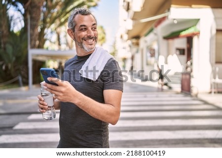 Middle age hispanic man wearing sportswear using smartphone at street Royalty-Free Stock Photo #2188100419