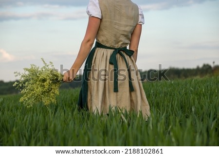 Linen dress in the field, girl with a bouquet in the field, girl with a field bouquet, beige Bavarian dress Royalty-Free Stock Photo #2188102861