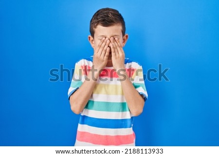 Young caucasian kid standing over blue background rubbing eyes for fatigue and headache, sleepy and tired expression. vision problem 