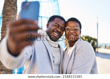 Man and woman couple standing together make selfie by the smartphone at street