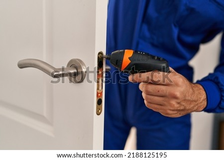 Young hispanic man technician repairing door at home