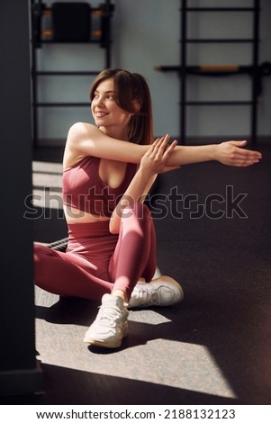Preparing for the exercises. Doing streching. Young beautiful woman in sportive clothes have fitness day in the gym. Royalty-Free Stock Photo #2188132123