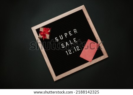 The text of the sale 12.12 on a letter board with a credit card. Design to promote the winter sale at the end of the year. Top view. Solid green background