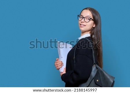 Teenage female student with backpack notebooks on color background