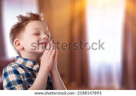 Christian child prayer to god on room background.