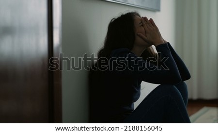 Woman feeling emotional pain sitting on floor home being desperate covering face with shame Royalty-Free Stock Photo #2188156045