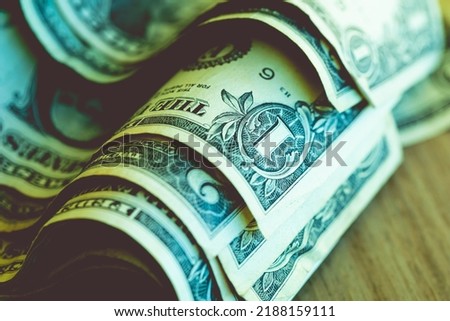 One dollar bills in macro photography that are on a wooden furniture. Economy and finance concepts.

