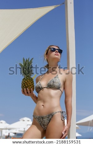 Happy young woman drinking fresh pineapple cocktail at the beach bar. Concept of tropical summer vacation.