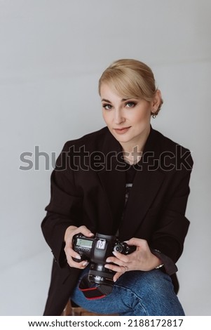 Beautiful woman photographer, journalist, posing with a camera in her hands. Soft selective focus.