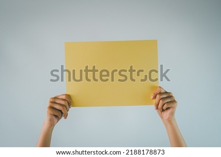 Mock Up Template photo concept.,Hand Holding Blank Yellow paper for banner,advertising isolated over white wall background.