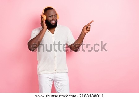 Photo of adorable pretty young man wear white shirt arm headwear enjoying music empty space isolated pink color background