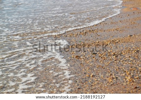 sea waves on a sandy beach with small pebbles