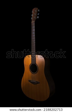 brown acoustic guitar on a black background. Guitar body part front made with top solid, side and back mahogany wood.