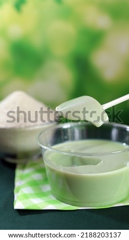 Avocado juice in a green glass and pudding from avocado fermented powder, backed with yellow napkin