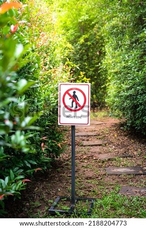 "Private zone" sign and symbol with human walking icon, placed in front of walk way and greenery tree plant background. Symbol object photo.