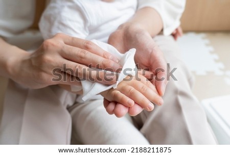 A women wipes baby's arm with wet tissue Royalty-Free Stock Photo #2188211875