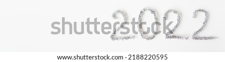 Baner happy new year 2022 written with foil and new year rain on an isolated white background. Selective focus, noise. Happy new year greetings