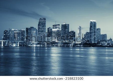 Miami skyline panorama at dusk with urban skyscrapers and bridge over sea with reflection 