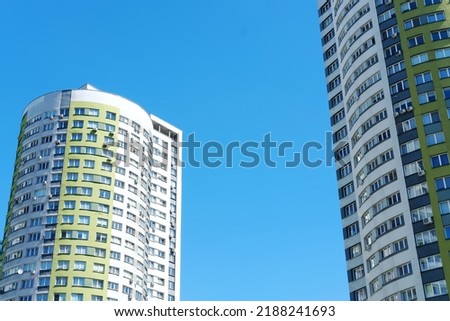 Multi-storey building in the form of a cylinder and painted in white and green colors against a blue sky.  Horizontal photo