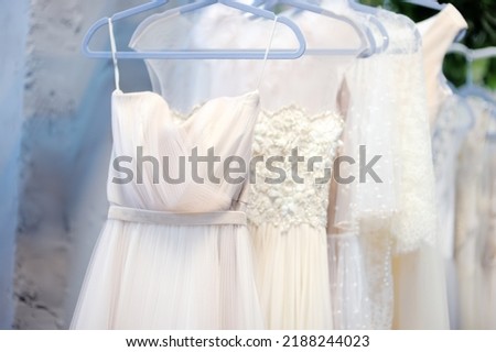 Few beautiful dresses on hanger in wedding salon or atelier sewing studio. Wedding exhibition or shop, evening and bridesmaid dresses. Holiday and events clothes rental. Personal sewing clothes Royalty-Free Stock Photo #2188244023