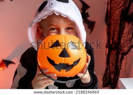 Halloween kids boy with pumpkin candy buckets in skeleton costume at home. Ready for trick or treat holiday.