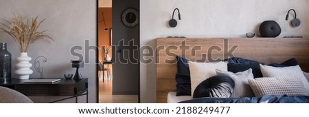 Panorama of elegant bedroom with cozy bed with wooden headboard, mirror in black frame and decorated desk Royalty-Free Stock Photo #2188249477