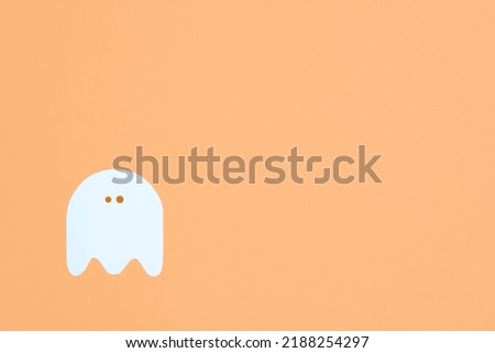 Minimalist halloween design, white cute ghost isolated on pastel orange color background, trendy composition with copy space.