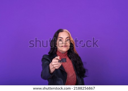 Woman showing a credit card on purple background. Shopping concept. Studio shot.