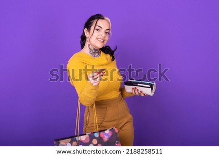 A women holding her wallet and shopping bag while showing a credit card.  Shopping concept. Studio shot.