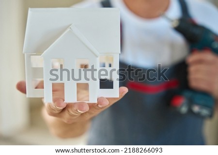 Close up photo of house model in builder hand and drill