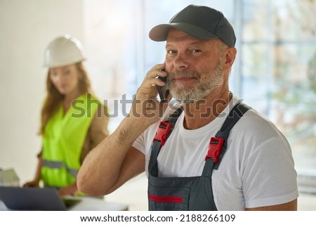 Photo of builder talking on phone. In background is realtor